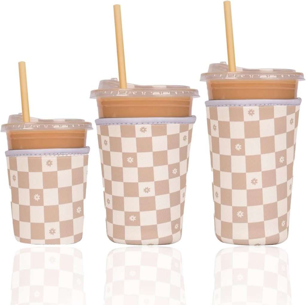 Three sizes of neoprene iced coffee cup sleeves in a neutral beige and white checkered daisy pattern, shown on iced coffee cups with straws — a cute and affordable just because gift under $20 featured in The Just Because Gift guide of 8 tiny thoughtful gestures