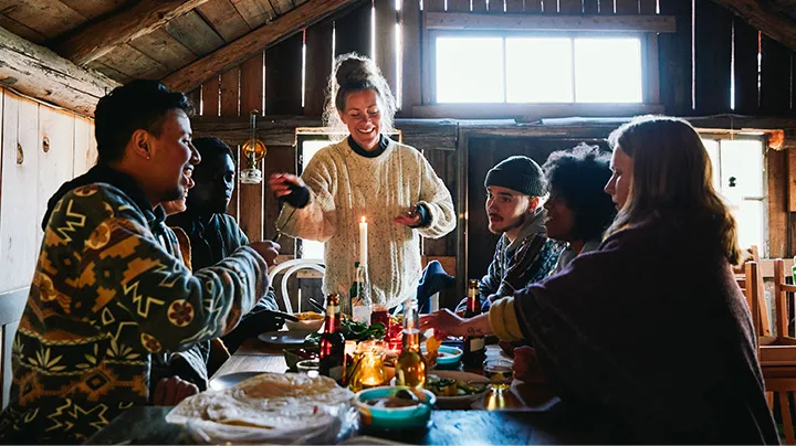 Friends celebrating together around a table, sharing a festive meal and exchanging gifts, reflecting Airawath’s smart gift suggestions and e-invitation experiences